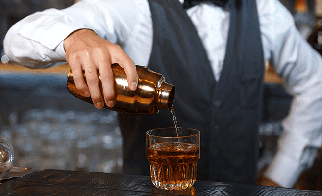 casino bartender pouring an alcoholic beverage