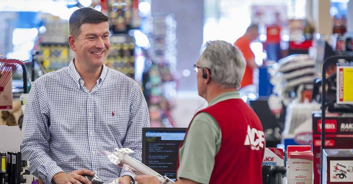 a hardware store associate is using the register to check out a smiling customer