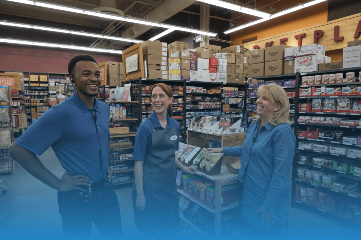 a team of 3 employees are standing in the aisle smiling