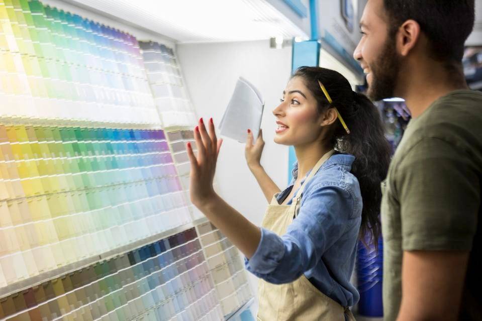 a hardware store employee assisting a customer in the paint samples department