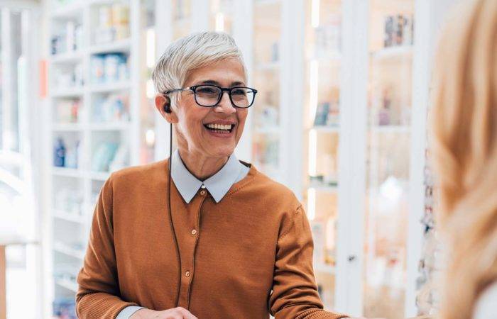 A retail employee wearing an earpiece, is smiling while helping a customer