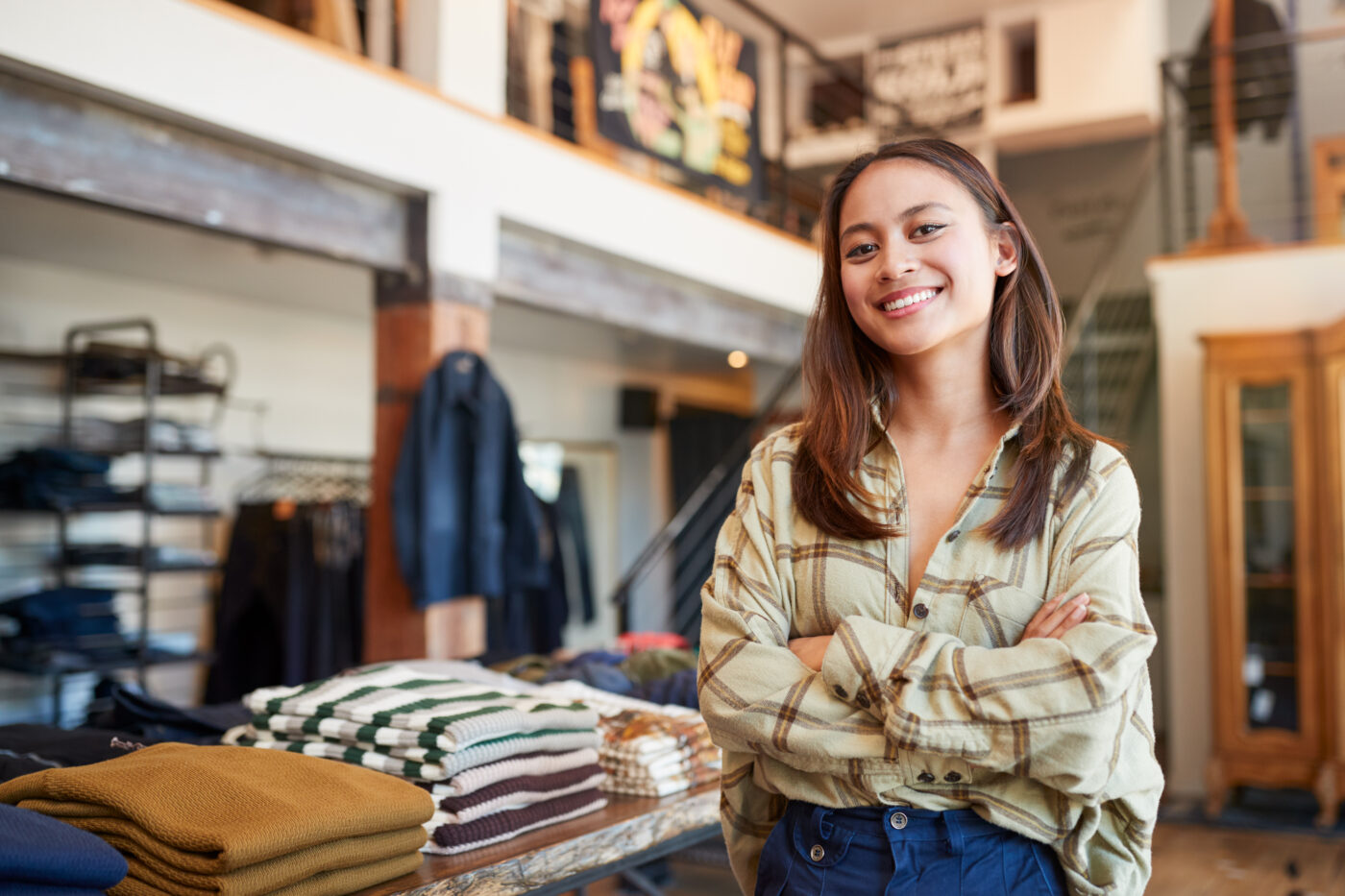 Portrait Of Smiling Female Owner Of Fashion Store Standing In Front Of Clothing Display