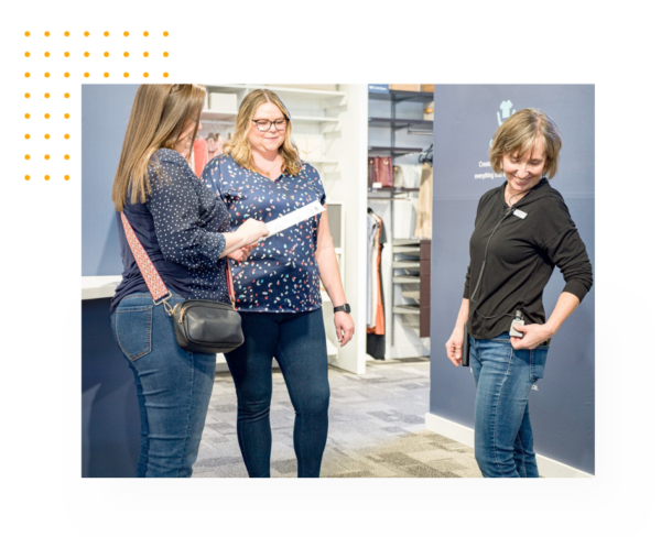 An employee helping 2 customers on the sales floor, while using Theatro.