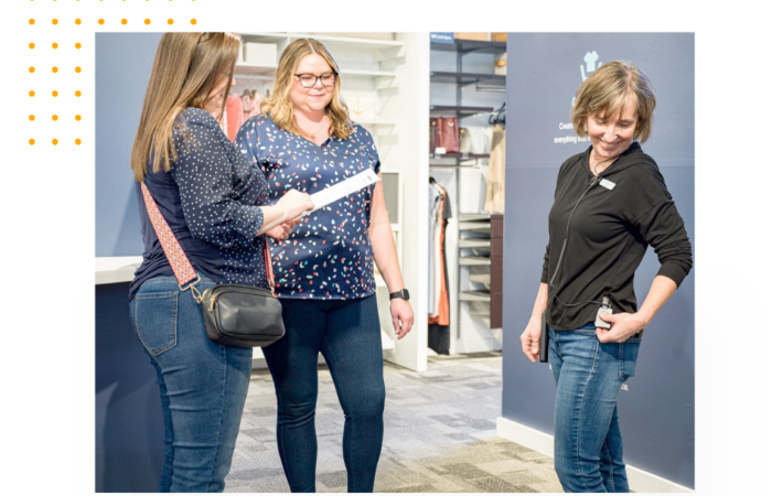 An employee helping 2 customers on the sales floor, while using Theatro.