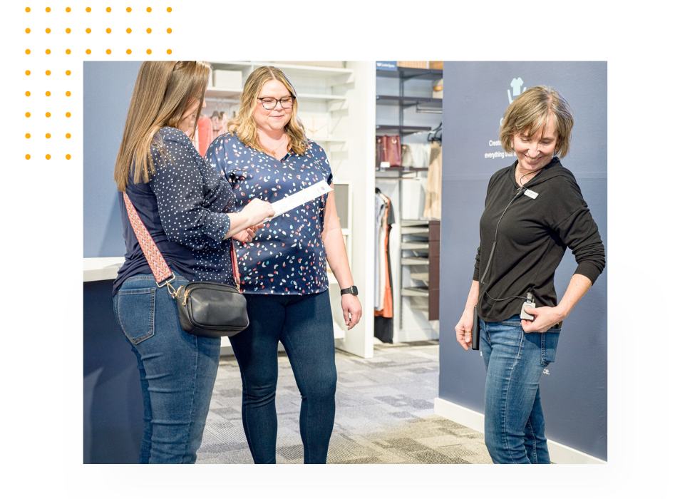 An employee helping 2 customers on the sales floor, while using Theatro.