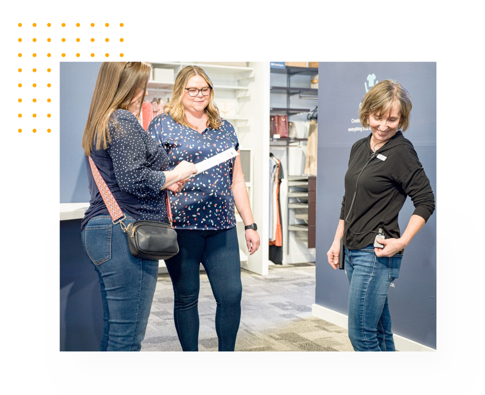 An employee helping 2 customers on the sales floor, while using Theatro.
