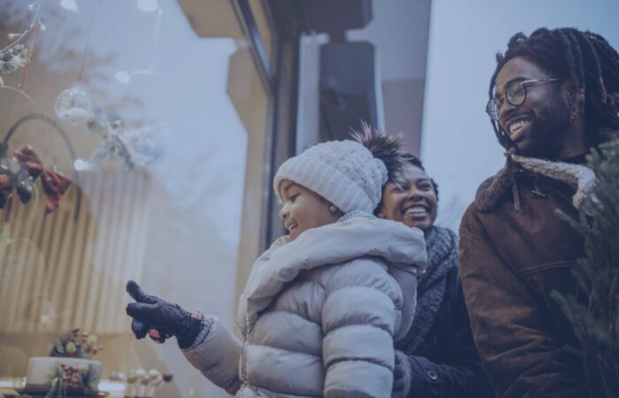 an african-american family window shopping and smiling while father is holding a christmas tree Theatro 2024 Holiday Shopping Report