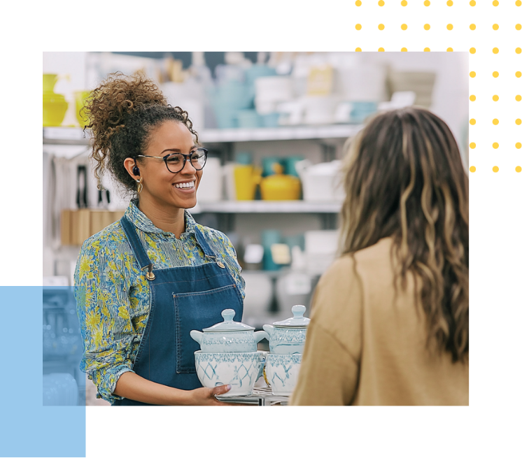 female retail employee smiling while holding kitchen ceramics